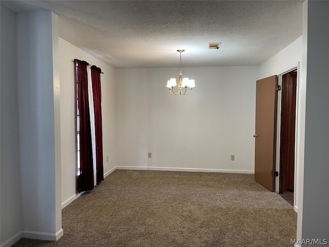 spare room featuring a textured ceiling, dark colored carpet, and an inviting chandelier