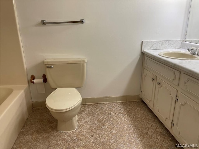 bathroom with toilet, baseboards, a bathtub, and vanity