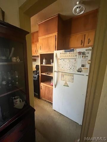 kitchen with stove, open shelves, and freestanding refrigerator