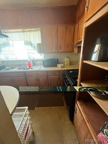 kitchen with stove, light countertops, and under cabinet range hood