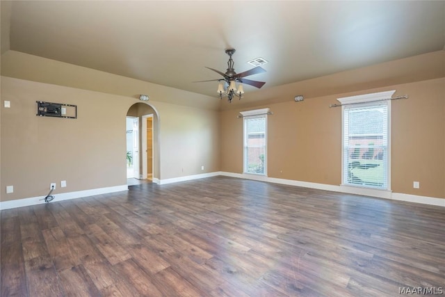 spare room with arched walkways, visible vents, ceiling fan, wood finished floors, and baseboards