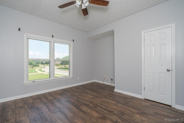 empty room featuring a ceiling fan, dark wood finished floors, and baseboards