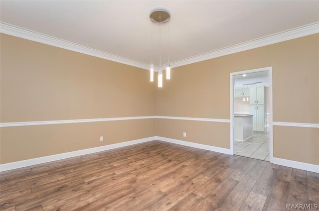 unfurnished room featuring ornamental molding, wood finished floors, and baseboards