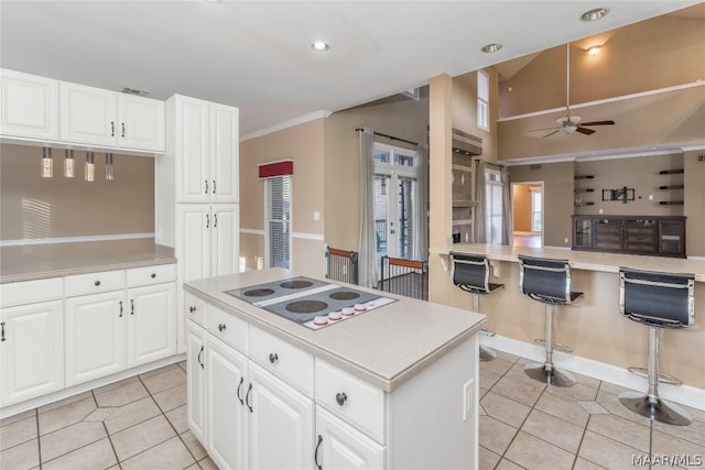 kitchen featuring light countertops, light tile patterned flooring, a kitchen island, and white electric stovetop