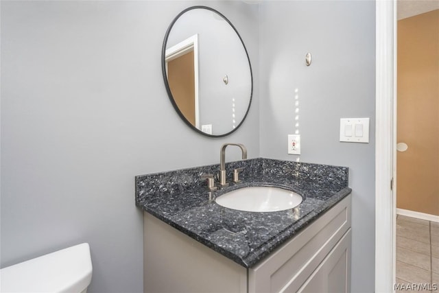 bathroom featuring toilet, tile patterned floors, baseboards, and vanity