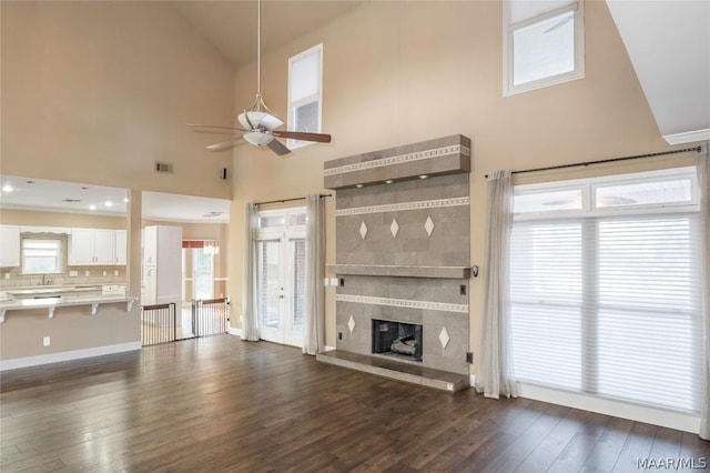 unfurnished living room with dark wood-style floors, a tile fireplace, visible vents, and a sink