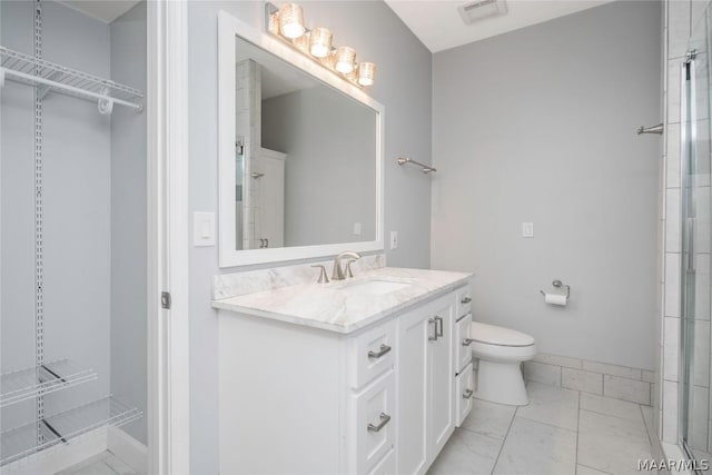 bathroom featuring toilet, vanity, visible vents, a spacious closet, and walk in shower