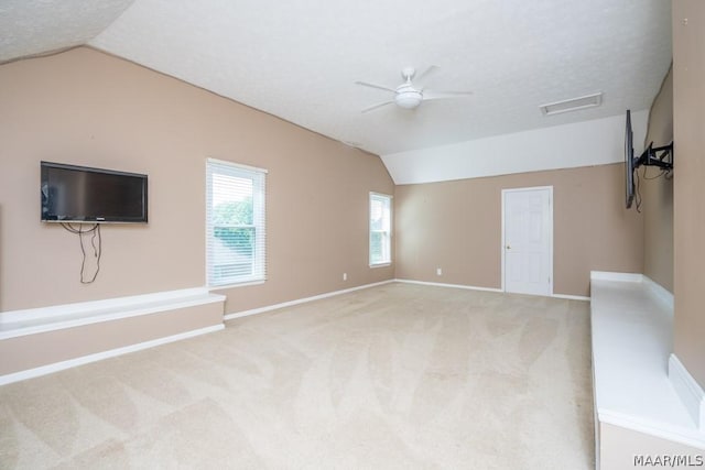 unfurnished living room featuring vaulted ceiling, carpet floors, a textured ceiling, and visible vents