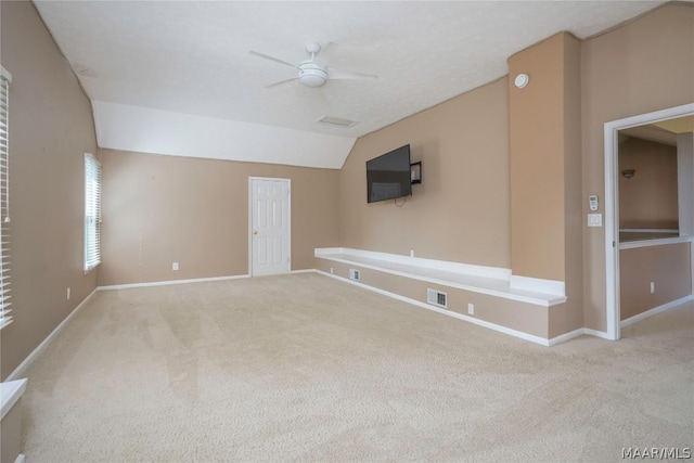 carpeted spare room with ceiling fan, visible vents, vaulted ceiling, and baseboards