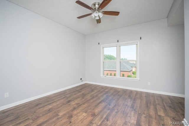 empty room featuring dark wood-style floors, a ceiling fan, and baseboards