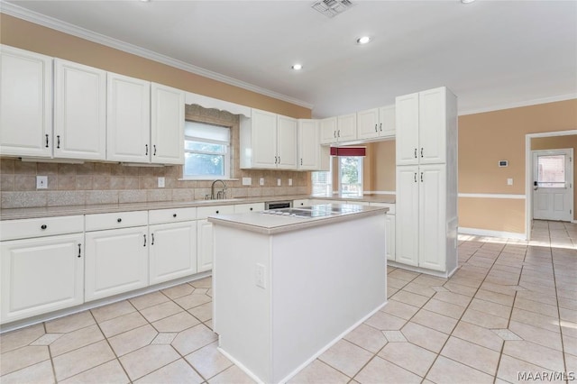 kitchen featuring light tile patterned floors, ornamental molding, light countertops, white cabinetry, and a sink