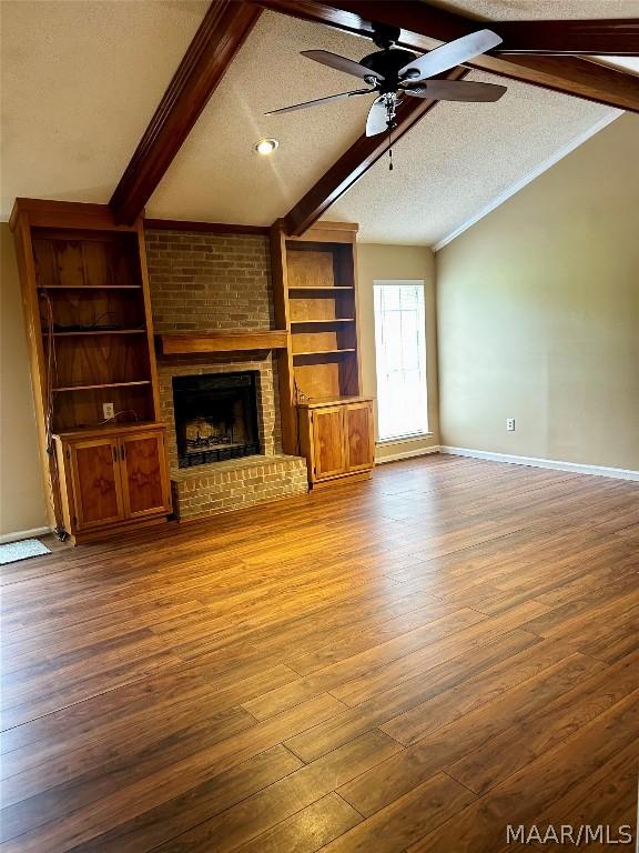 unfurnished living room featuring ceiling fan, a brick fireplace, vaulted ceiling with beams, a textured ceiling, and hardwood / wood-style flooring