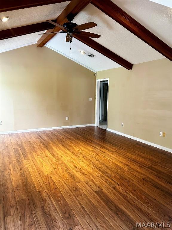 spare room with hardwood / wood-style flooring, vaulted ceiling with beams, ceiling fan, and a textured ceiling