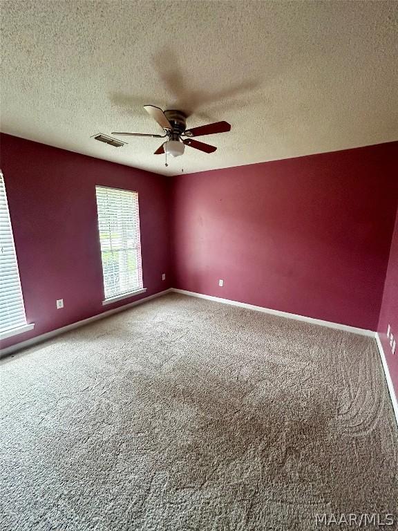 carpeted spare room featuring a textured ceiling and ceiling fan