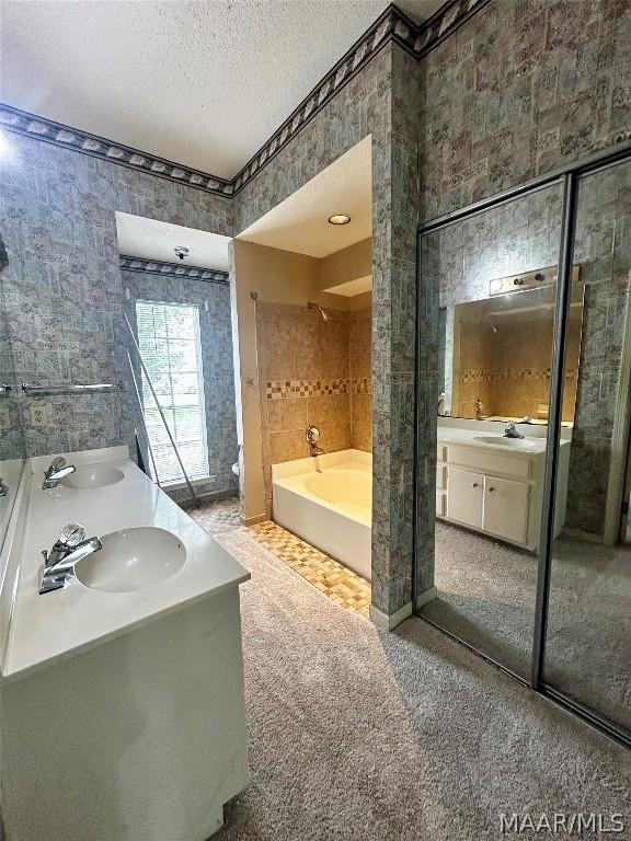 bathroom featuring vanity, shower with separate bathtub, and a textured ceiling