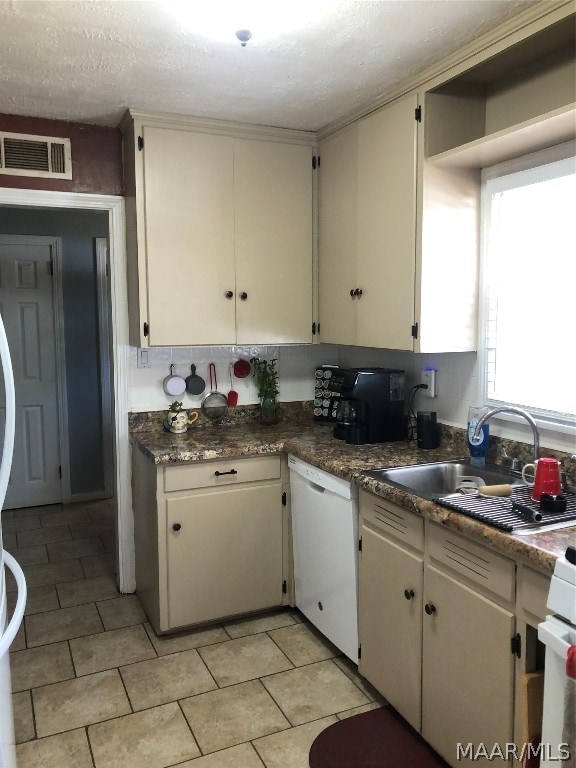 kitchen with light tile patterned flooring, sink, a textured ceiling, and white dishwasher