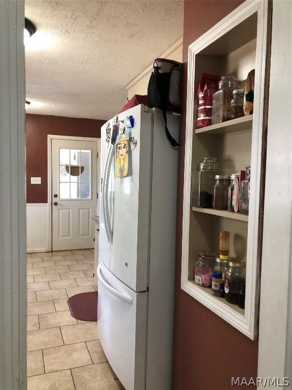 kitchen with white fridge, a textured ceiling, and light tile patterned flooring