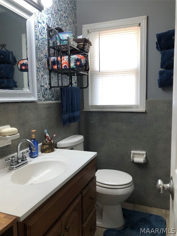 bathroom featuring tile walls, a healthy amount of sunlight, decorative backsplash, toilet, and vanity