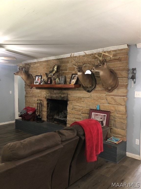 living room featuring a stone fireplace, crown molding, and dark hardwood / wood-style floors