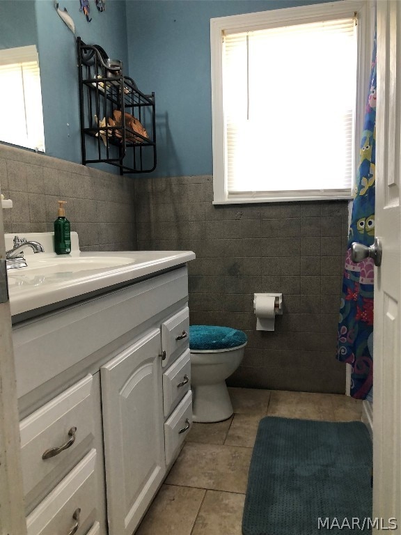 bathroom with vanity, toilet, a wealth of natural light, and tile walls