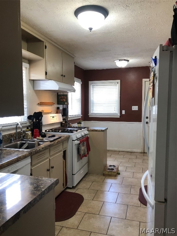 kitchen featuring light tile patterned flooring, sink, a textured ceiling, and white appliances