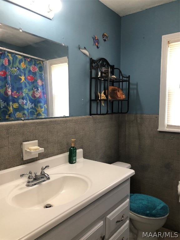 bathroom featuring vanity, tasteful backsplash, toilet, and tile walls