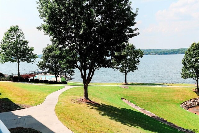 surrounding community with a water view and a lawn