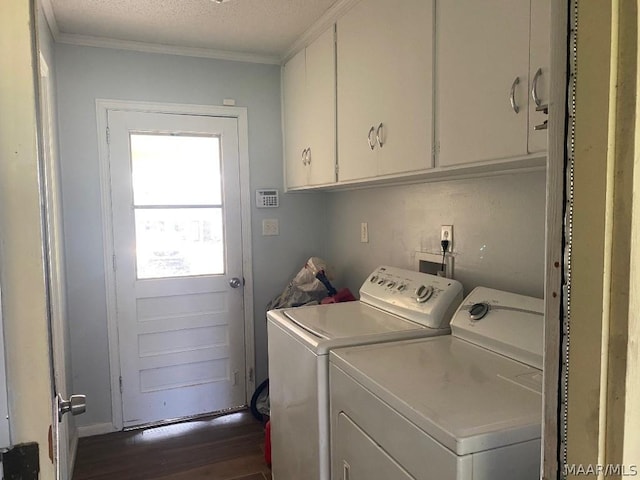 clothes washing area with washing machine and clothes dryer, dark wood-type flooring, a textured ceiling, cabinets, and crown molding