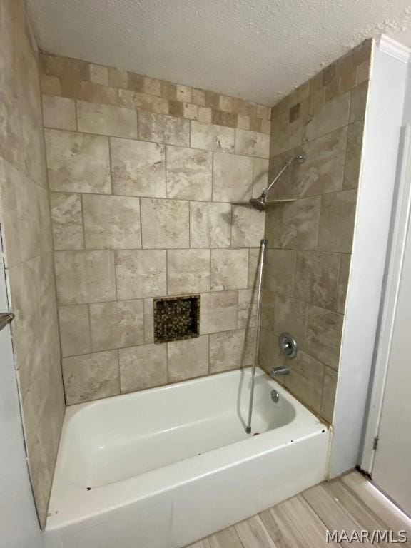 bathroom with tiled shower / bath and a textured ceiling