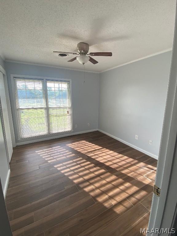 unfurnished room featuring ceiling fan, a textured ceiling, dark hardwood / wood-style floors, and ornamental molding