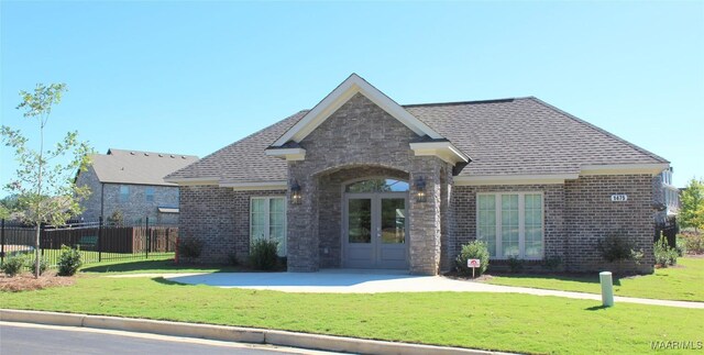 view of front of property featuring french doors, brick siding, and roof with shingles