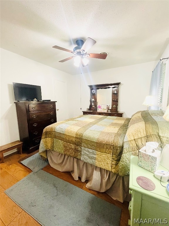 bedroom featuring a textured ceiling, wood-type flooring, and ceiling fan