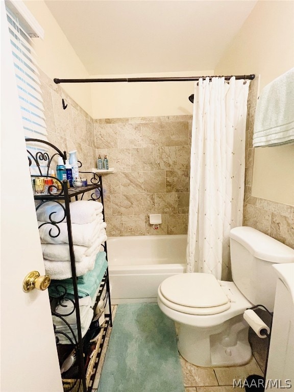 bathroom featuring toilet, tile patterned floors, tile walls, and shower / bath combo