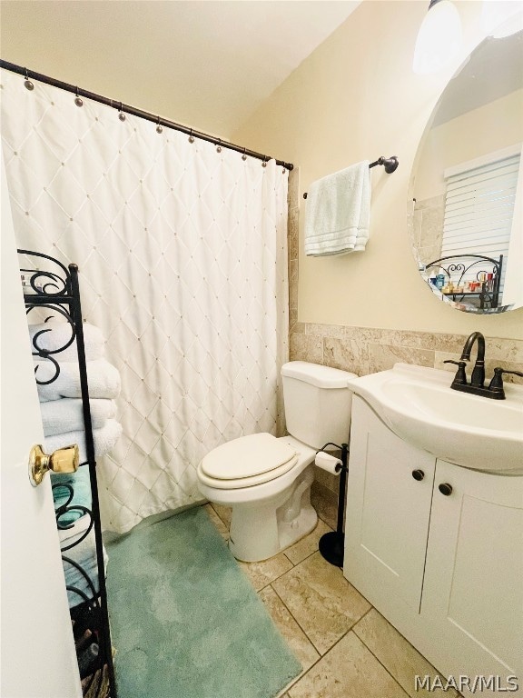 bathroom featuring tile walls, toilet, vanity, a shower with shower curtain, and tile patterned flooring