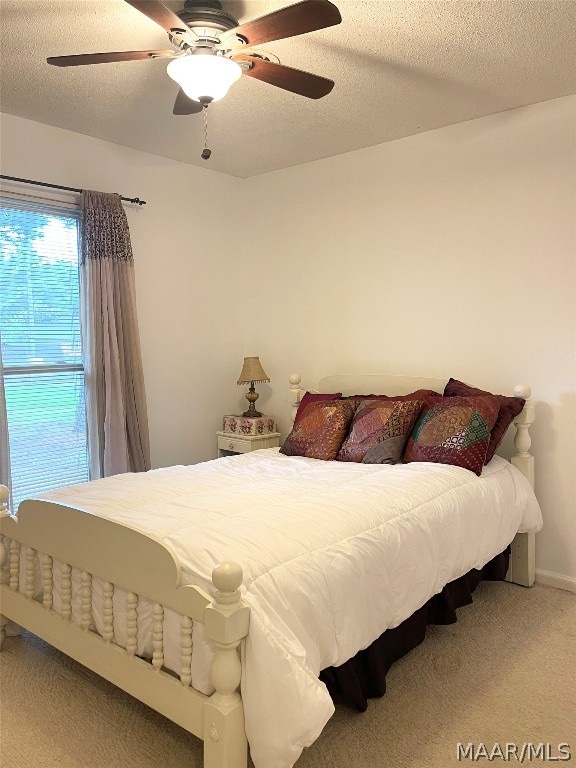 carpeted bedroom featuring a textured ceiling and ceiling fan