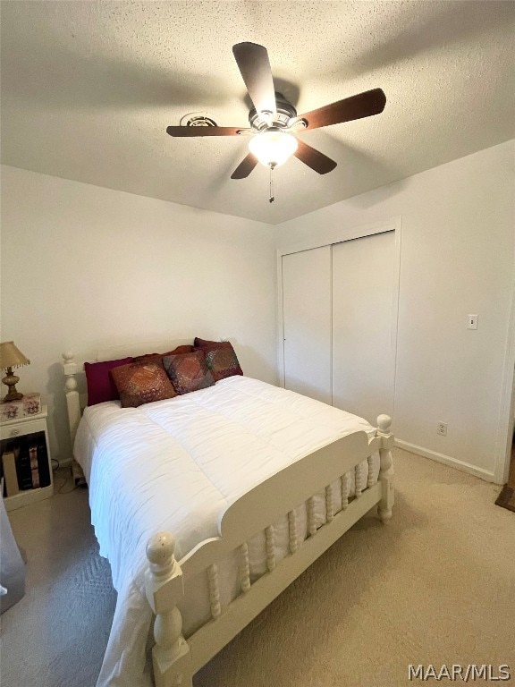 bedroom featuring a textured ceiling, carpet flooring, a closet, and ceiling fan