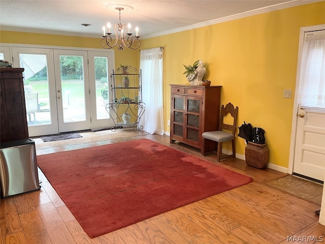 doorway featuring french doors, hardwood / wood-style flooring, ornamental molding, a notable chandelier, and a textured ceiling