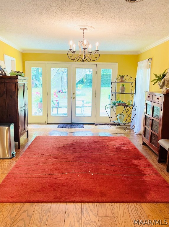 interior space featuring french doors, a notable chandelier, crown molding, and a textured ceiling