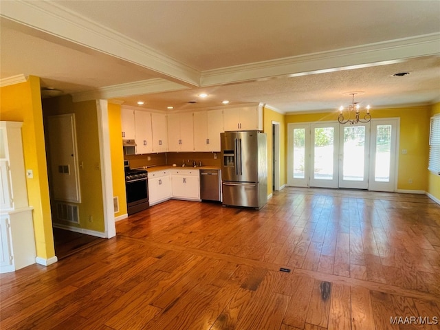 kitchen with hardwood / wood-style floors, white cabinets, appliances with stainless steel finishes, ornamental molding, and sink