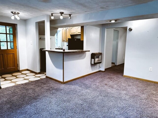 kitchen featuring kitchen peninsula, carpet floors, black fridge, heating unit, and a textured ceiling