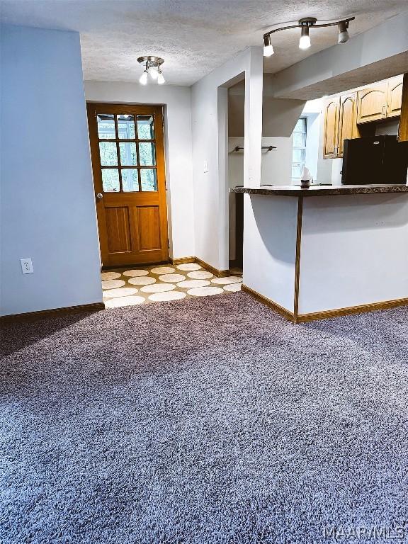 kitchen featuring light colored carpet, kitchen peninsula, a textured ceiling, and black fridge