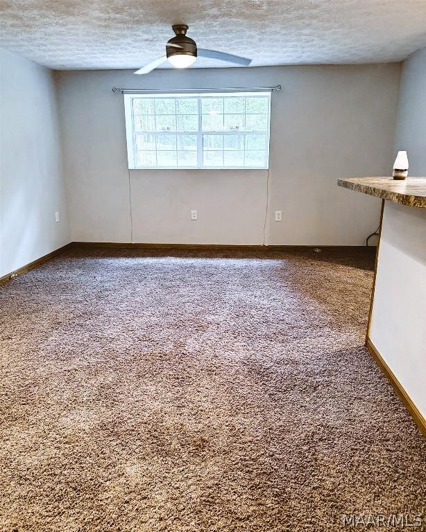 carpeted spare room with ceiling fan and a textured ceiling