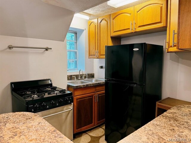 kitchen with stainless steel gas stove, black refrigerator, and sink