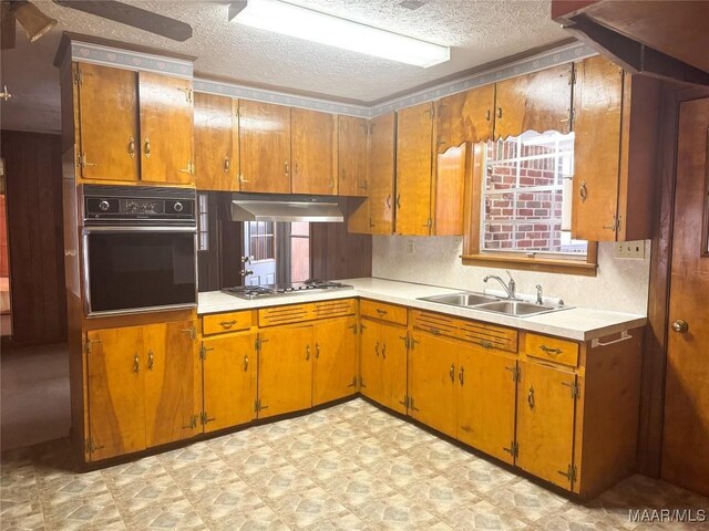 kitchen featuring black oven, stainless steel gas cooktop, sink, and a textured ceiling