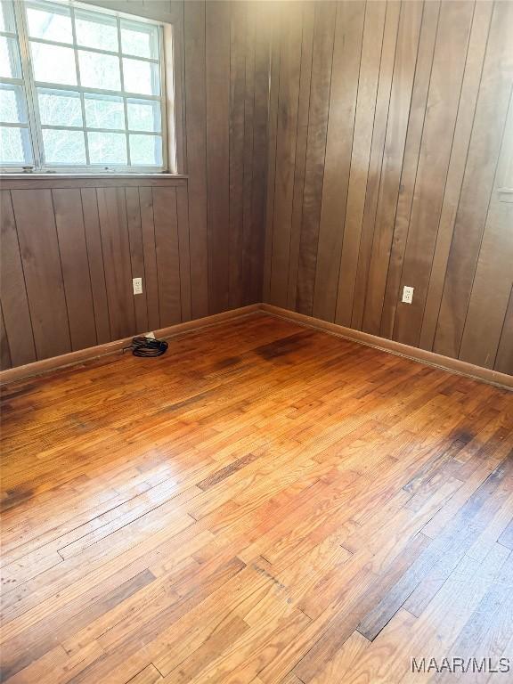 spare room featuring wood walls and light wood-type flooring