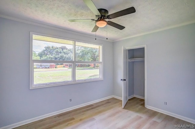 unfurnished bedroom with ceiling fan, ornamental molding, a closet, and light wood-type flooring