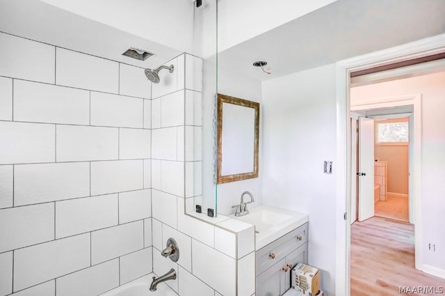 bathroom with hardwood / wood-style flooring, vanity, and tiled shower / bath combo