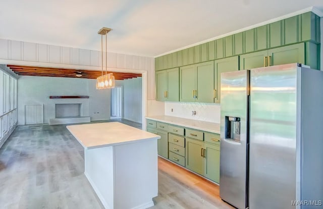 kitchen with a kitchen island, pendant lighting, stainless steel fridge, green cabinetry, and light hardwood / wood-style flooring