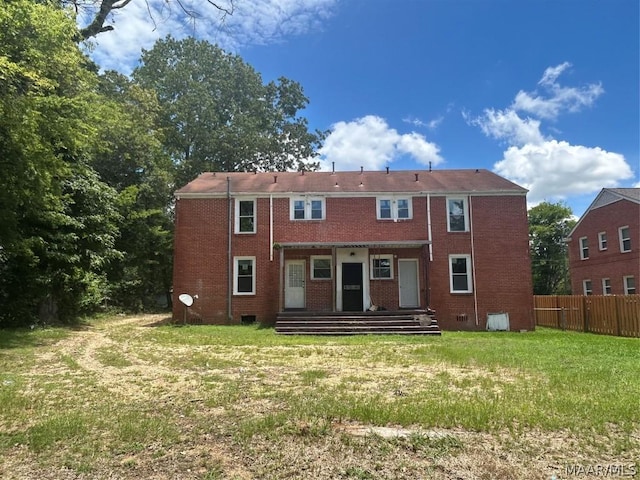 rear view of property with brick siding, a yard, entry steps, crawl space, and fence