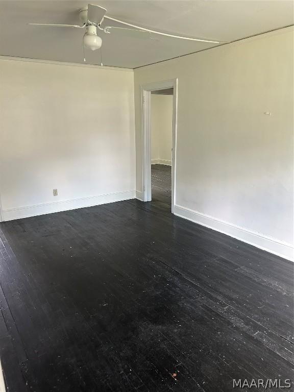 empty room featuring ceiling fan, baseboards, and dark wood-type flooring